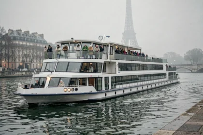 Bateau de croisière fluviale naviguant sur la Seine à Paris avec la Tour Eiffel en arrière-plan dans la brume matinale
