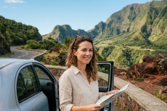 Femme consultant une carte routière à côté d'une voiture de location avec vue sur les montagnes volcaniques de La Réunion
