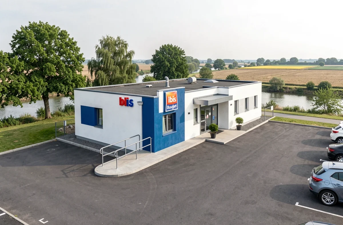 Extérieur de l'Hôtel Ibis Budget Dole avec facade moderne bleue et blanche dans une zone commerciale proche du canal