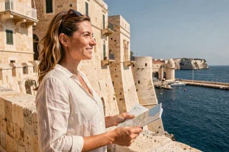 Touriste tenant une carte devant les remparts de La Valette à Malte avec vue sur le Grand Port